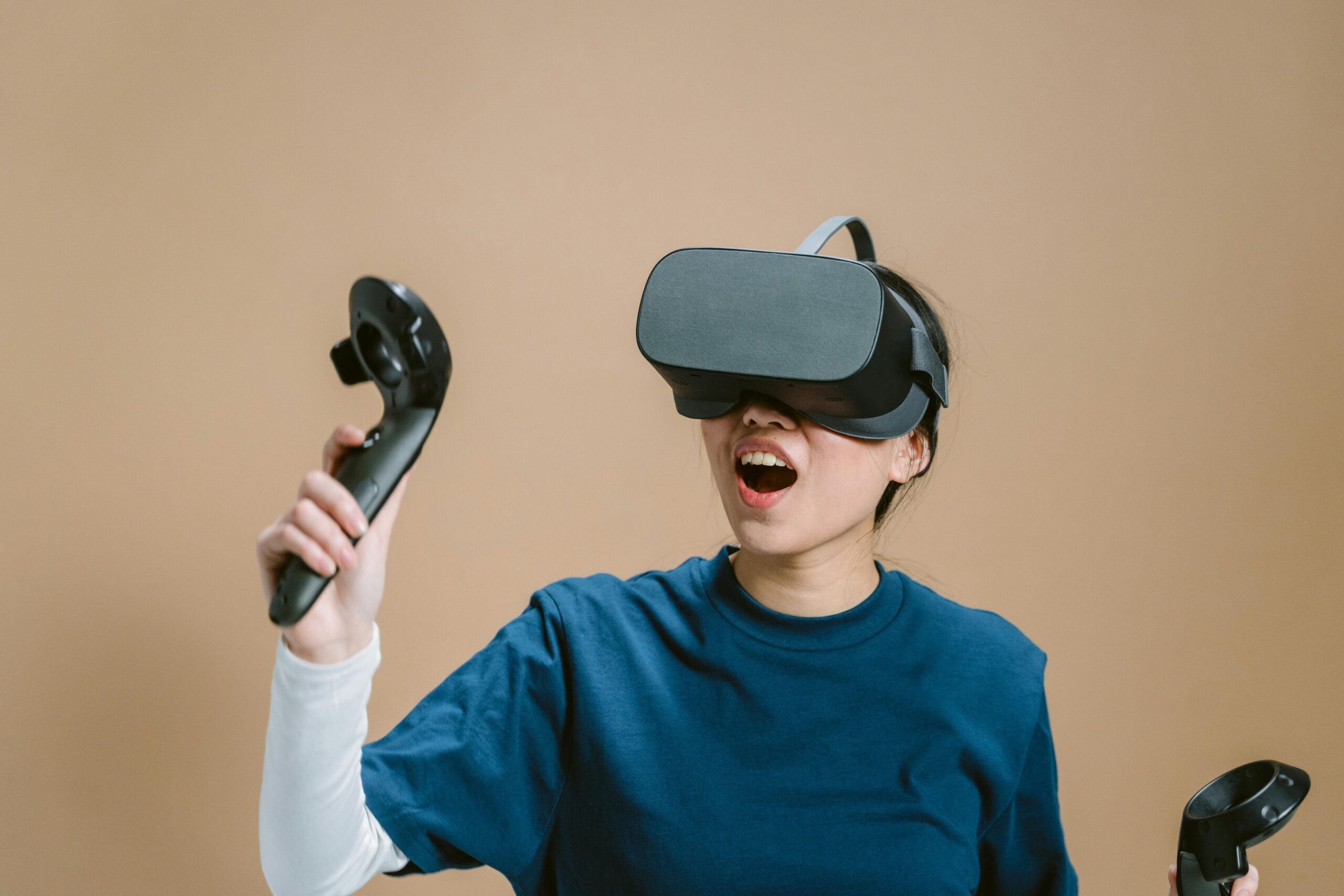 Teen experiencing virtual reality gaming excitement indoors with VR headset and controllers.